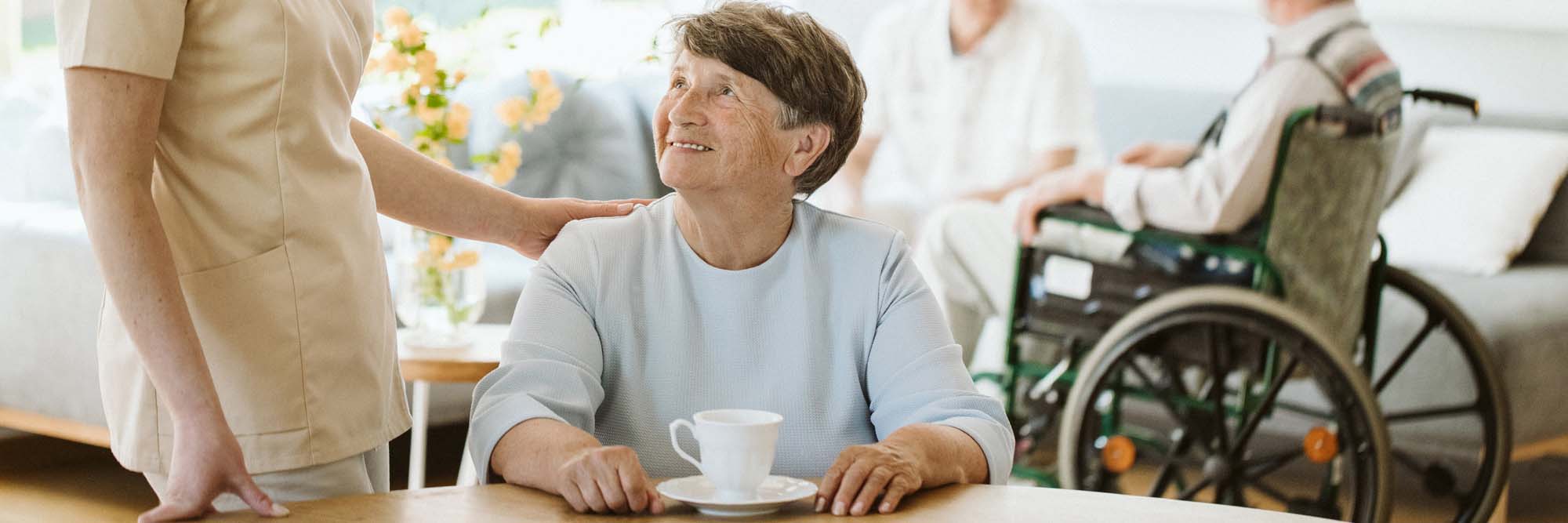 Happy senior woman and helpful caregiver, nursing home concept p